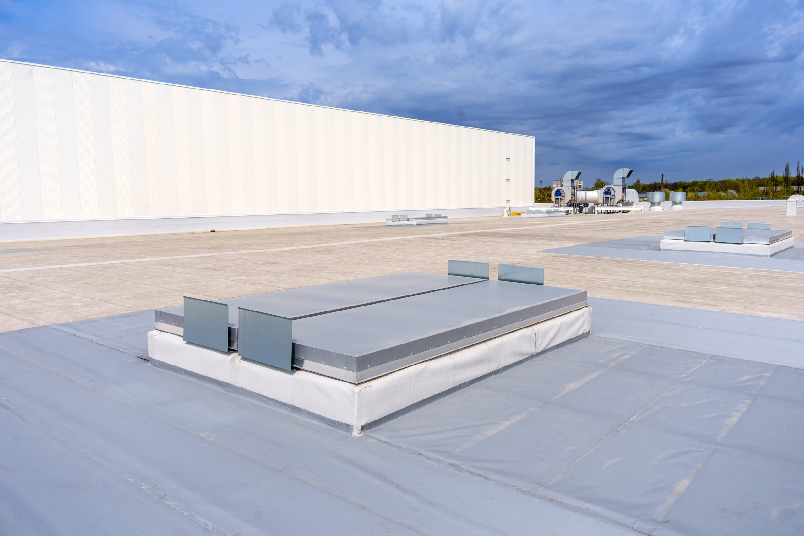 White metal sheet rooftop wall on commercial building with blue sky.